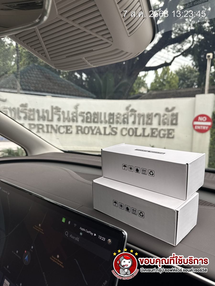 กล่องเครื่องสแกนบาร์โค้ด 2 กล่องวางบนคอนโซลรถ ด้านหลังเป็นป้ายโรงเรียนปรินส์รอยแยลส์วิทยาลัย